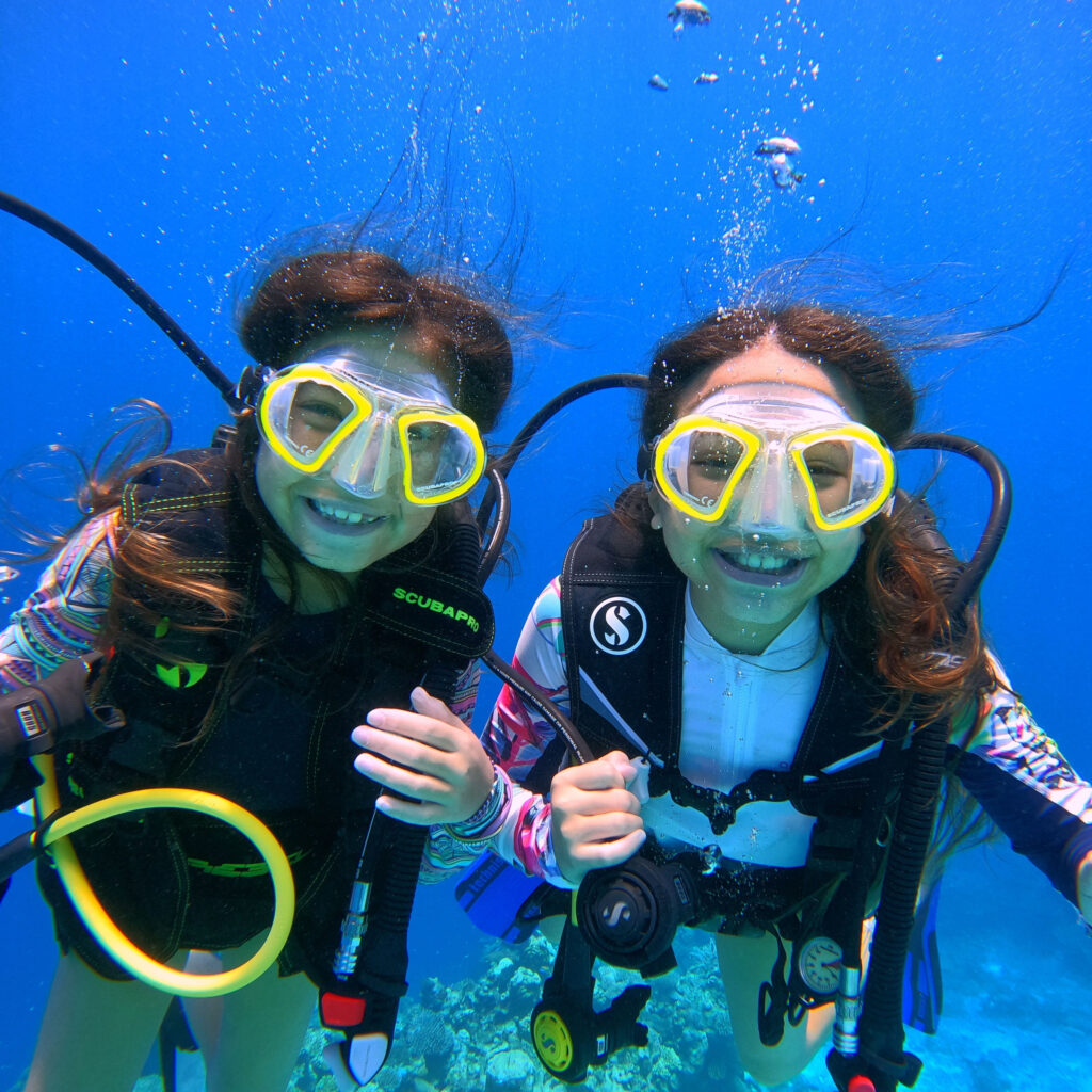 Two smiling girls underwater